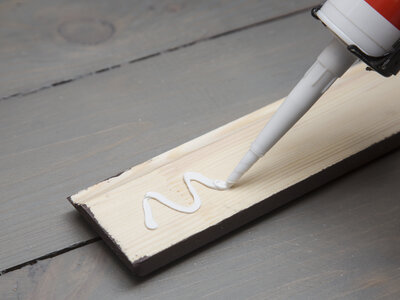 putting glue on a piece of wooden baseboard putting glue on a piece of wooden baseboard