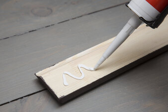 putting glue on a piece of wooden baseboard putting glue on a piece of wooden baseboard